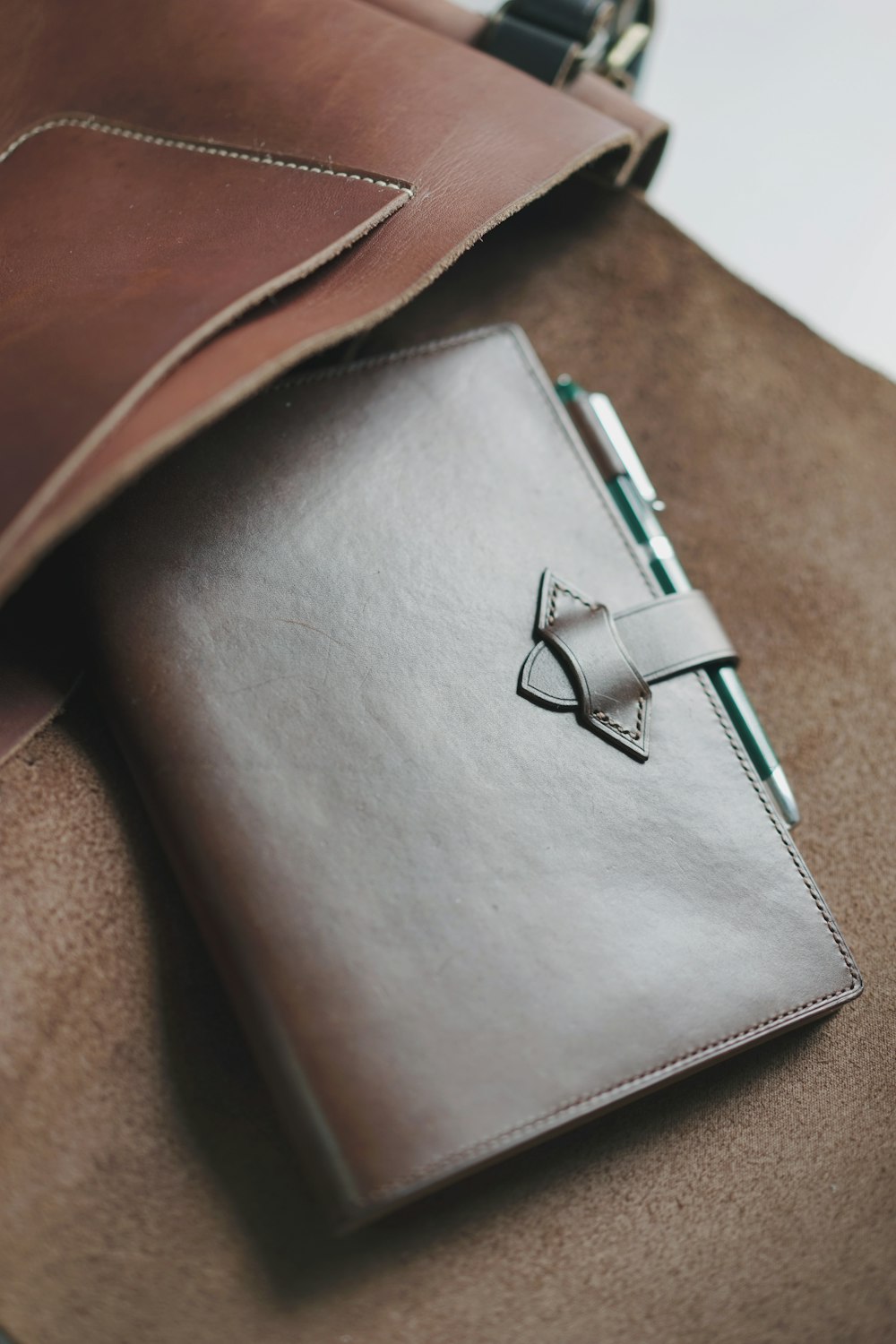 a brown leather notebook with a pen on top of it
