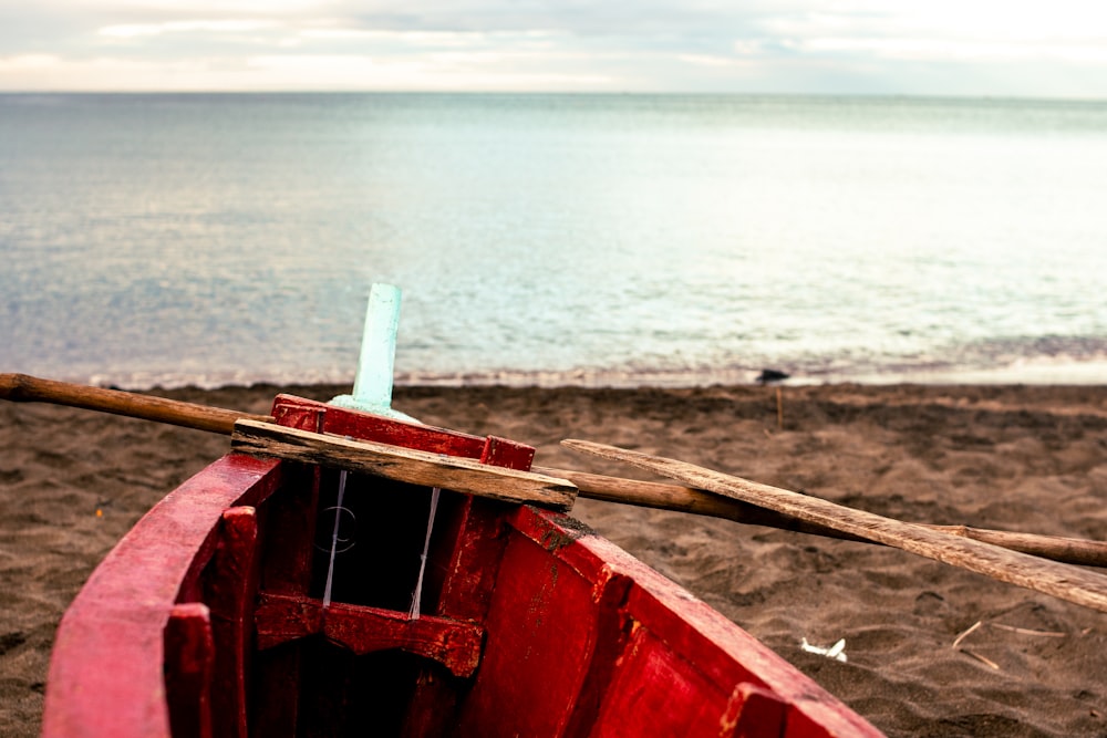 a red boat sitting on top of a sandy beach