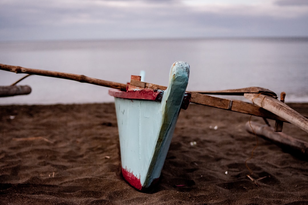 a boat sitting on top of a sandy beach,