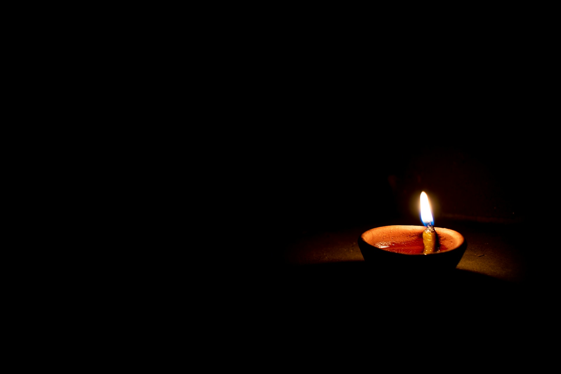 a lit candle sitting in the dark on a table