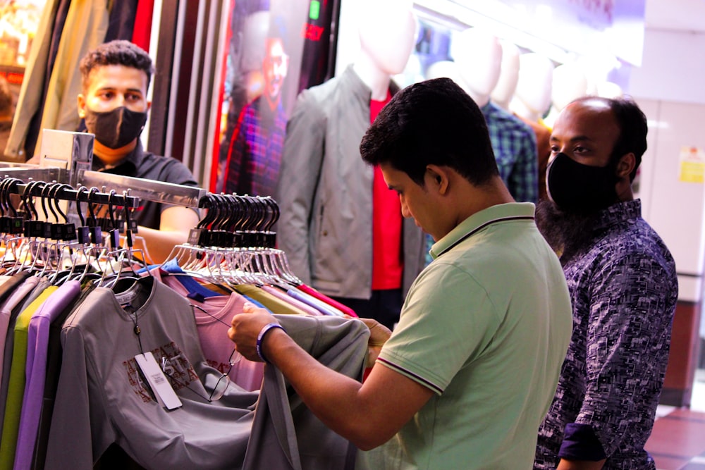 um homem olhando para uma camisa em um rack em uma loja