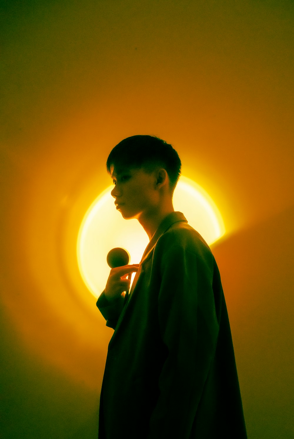 a man holding a microphone in front of a yellow light