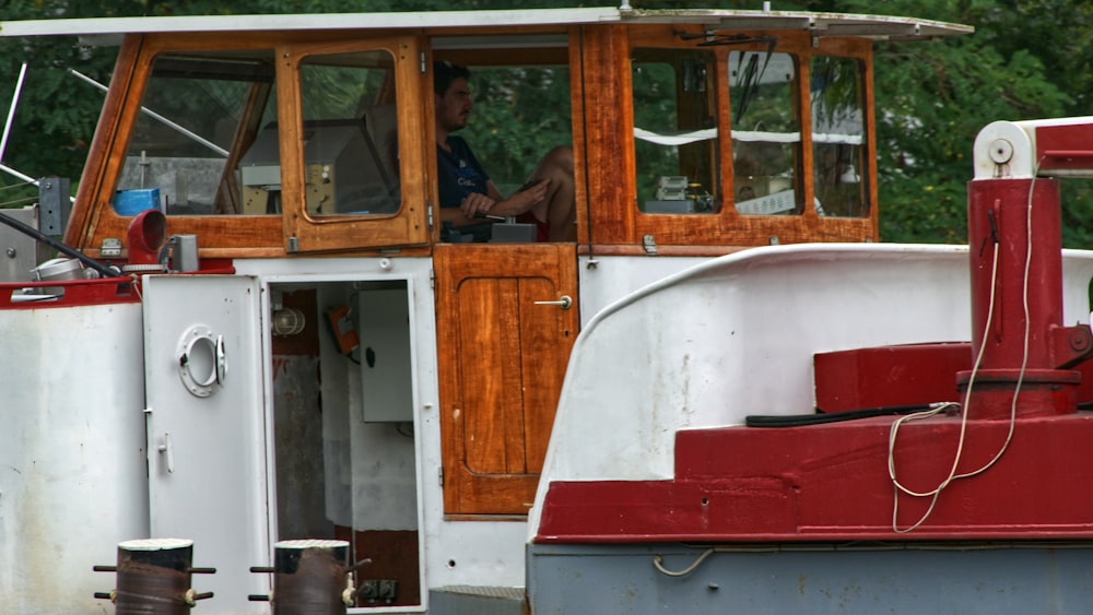 a red and white boat sitting next to a forest