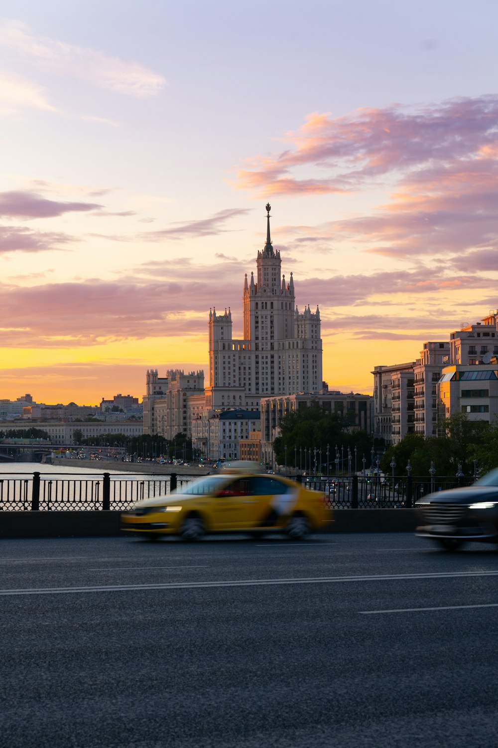 a yellow car driving down a street next to tall buildings