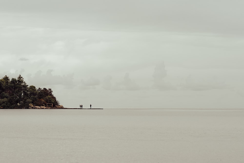 two people standing on a small island in the middle of the ocean