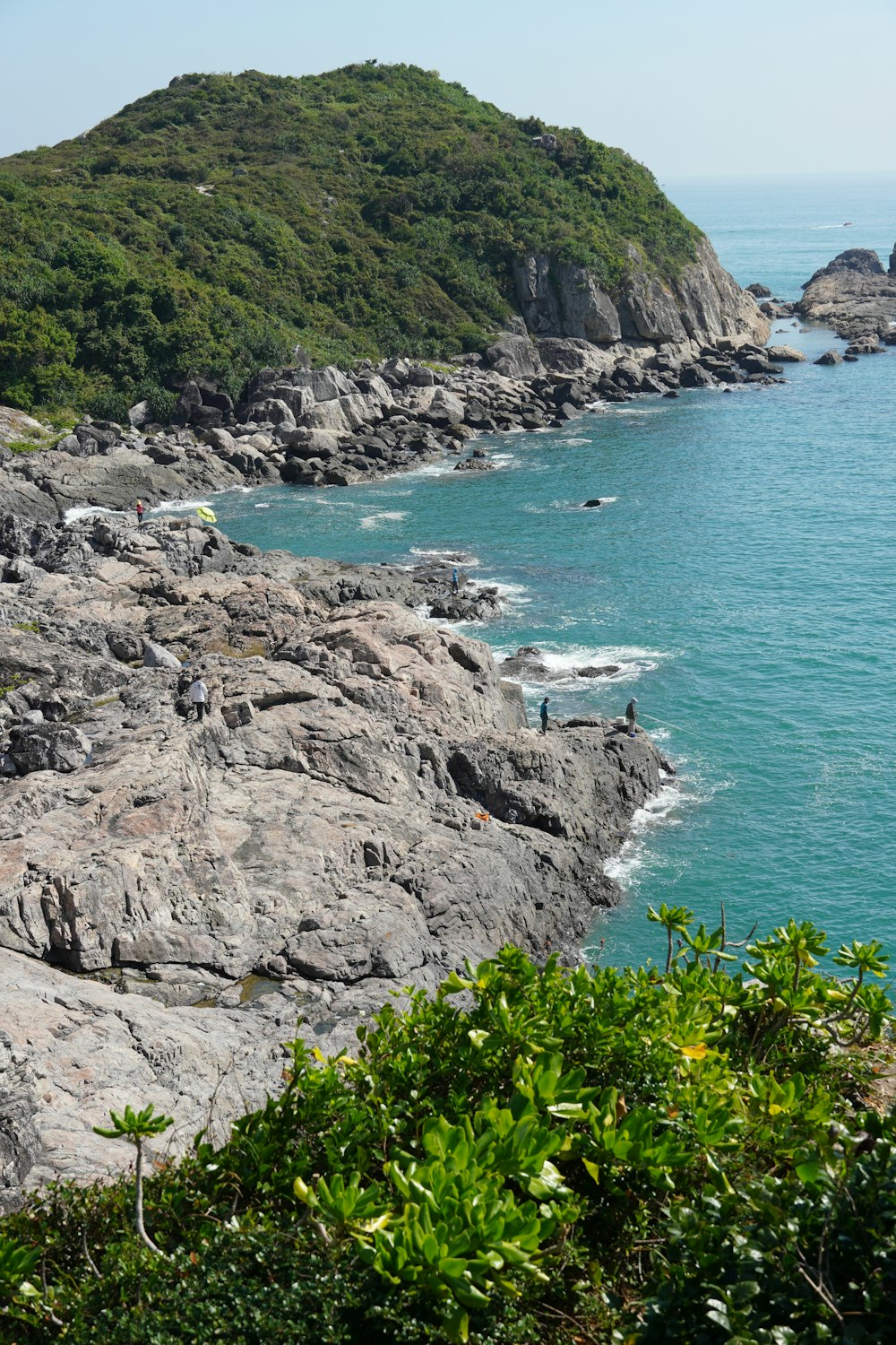 a group of people standing on top of a cliff next to the ocean