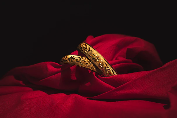 Elegant gold bangles stacked gracefully on a beige silk cloth with gentle reflections highlighting their craftsmanship