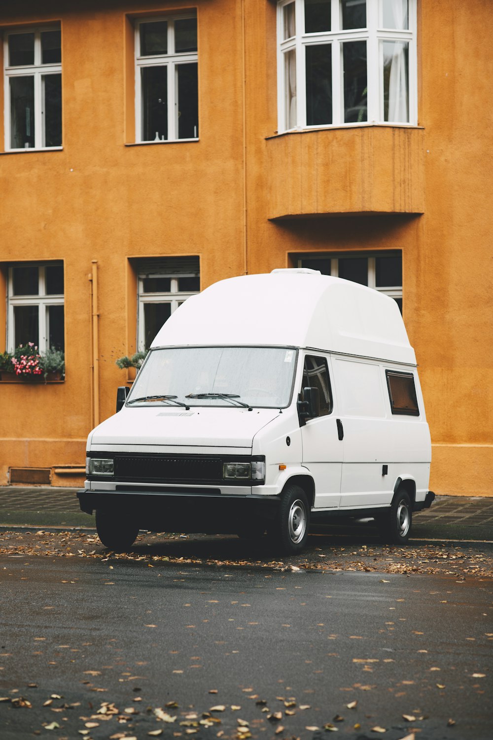 Ein weißer Lieferwagen parkt vor einem gelben Gebäude