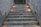 A staircase with motivational and relationship-themed phrases written on each step. The setting is outdoors, surrounded by concrete walls and minimal lighting. At the top, there is greenery visible.
