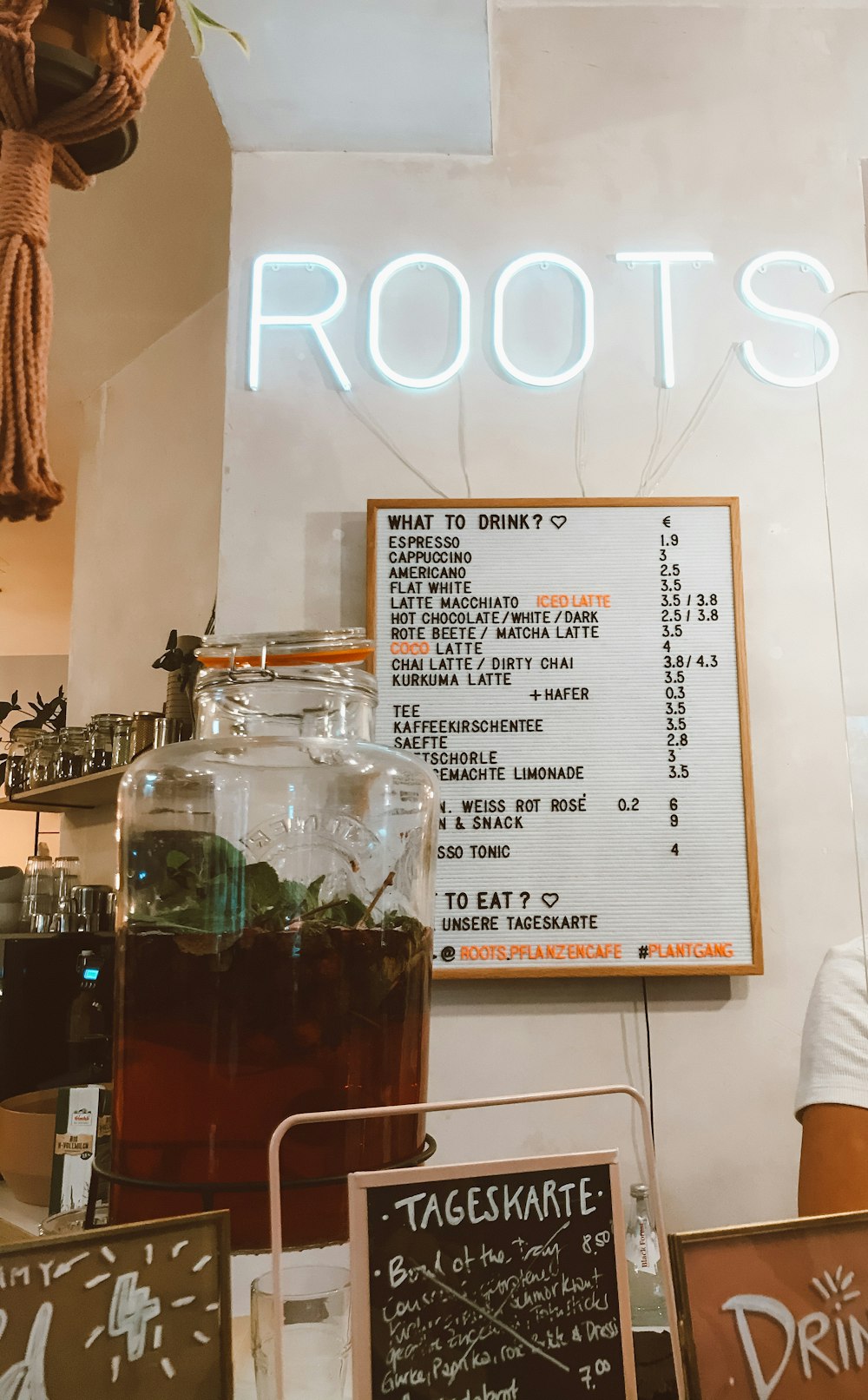 a sign that says roots above a table with drinks