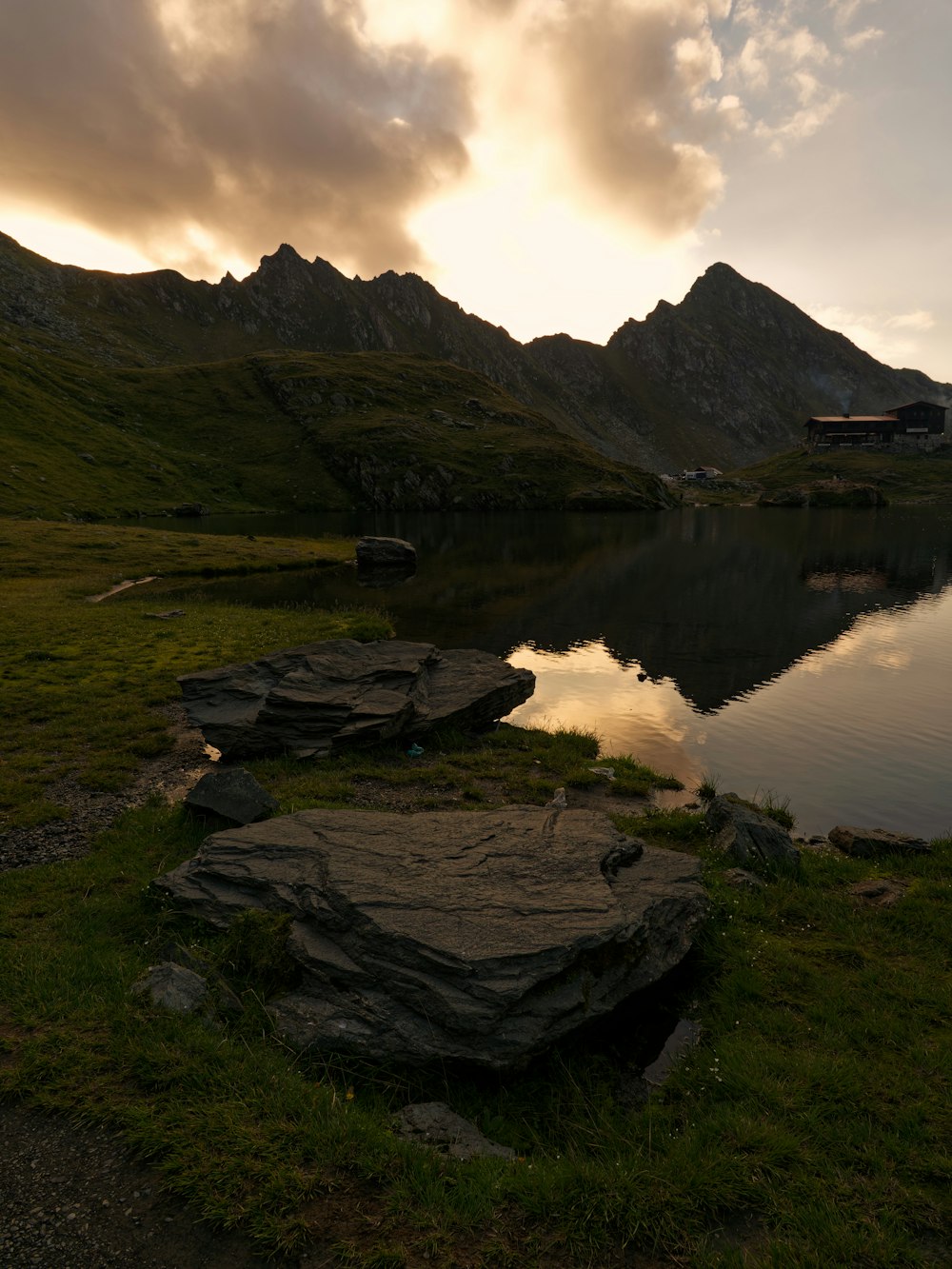 a body of water surrounded by mountains under a cloudy sky