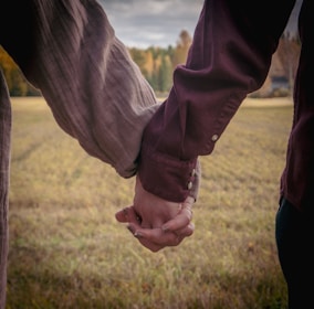 a man and woman holding hands in a field