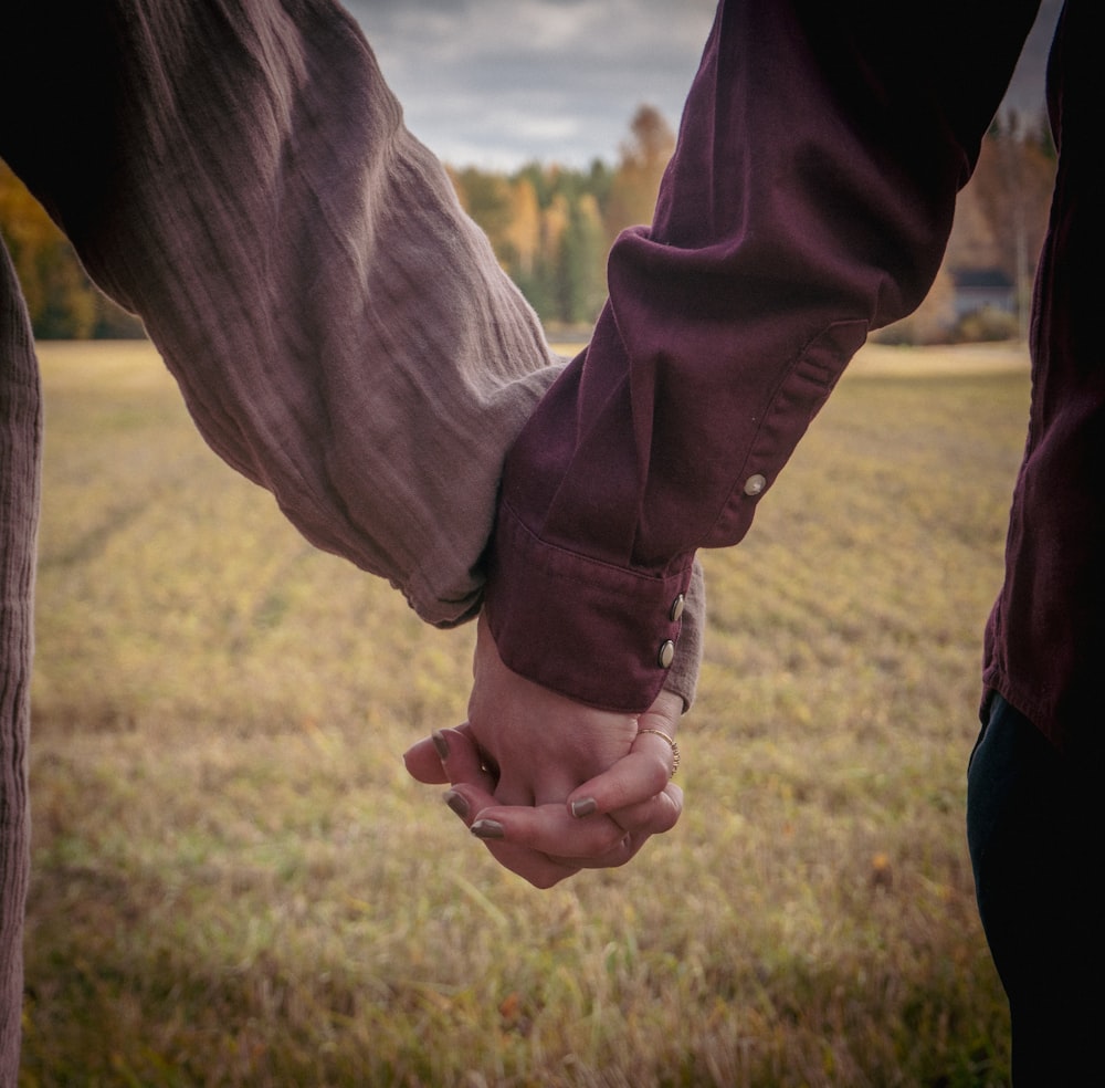 a man and woman holding hands in a field