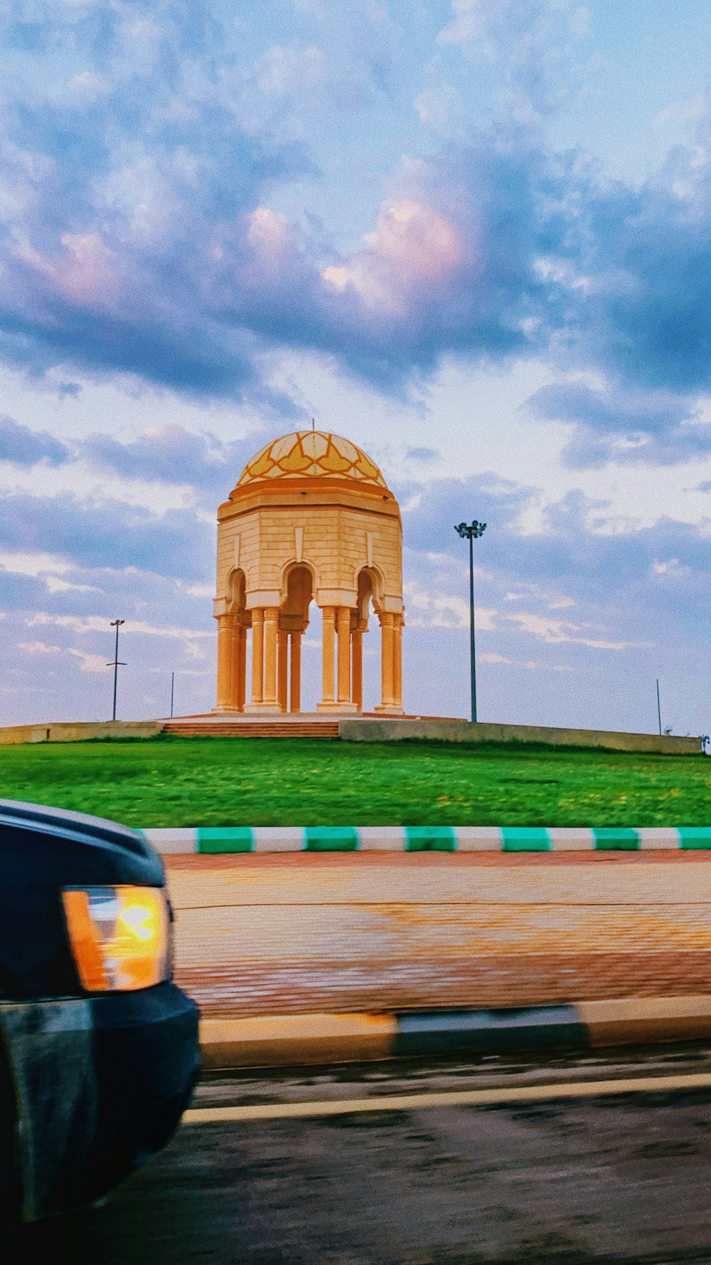 a car driving down a road past a monument