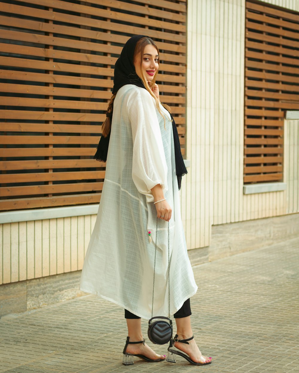 a woman in a white dress is standing on a sidewalk