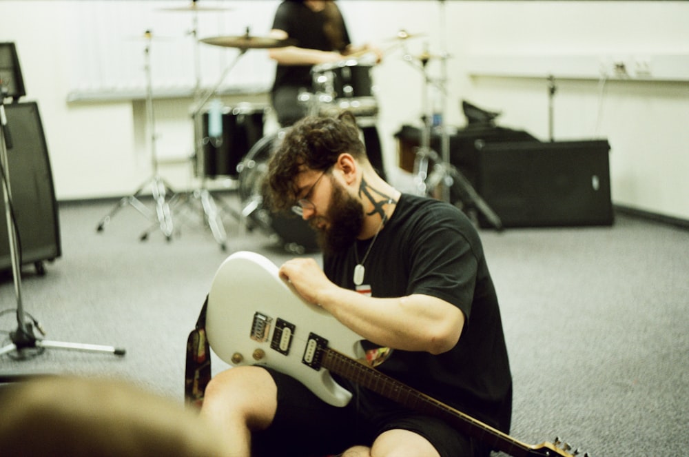 a man sitting on the floor playing a guitar