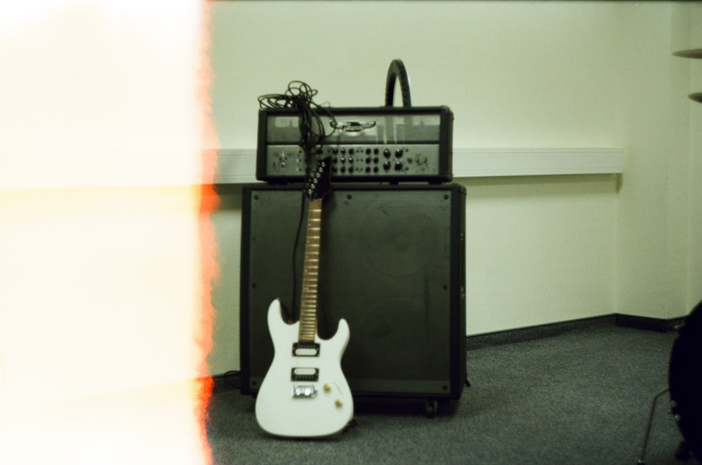 a white guitar sitting in front of a amplifier