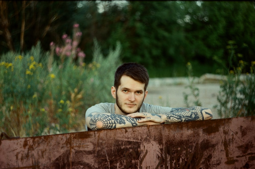 a man with tattoos leaning on a rusted rail