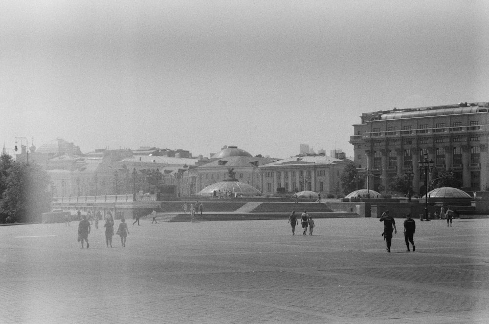 a black and white photo of people walking in a plaza