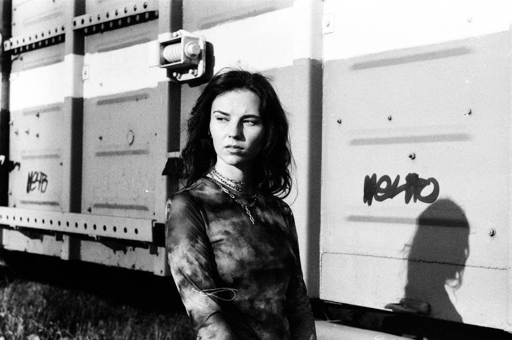 a black and white photo of a woman standing in front of a truck