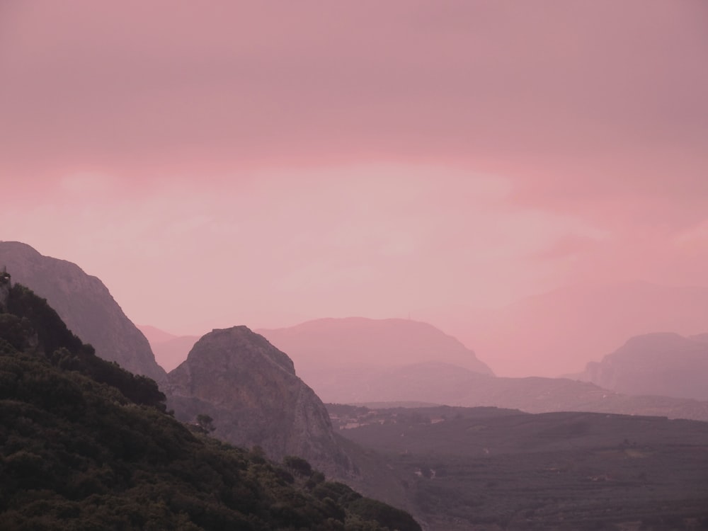 a pink sky over a mountain range at dusk