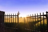 the sun is setting behind a fence in a field