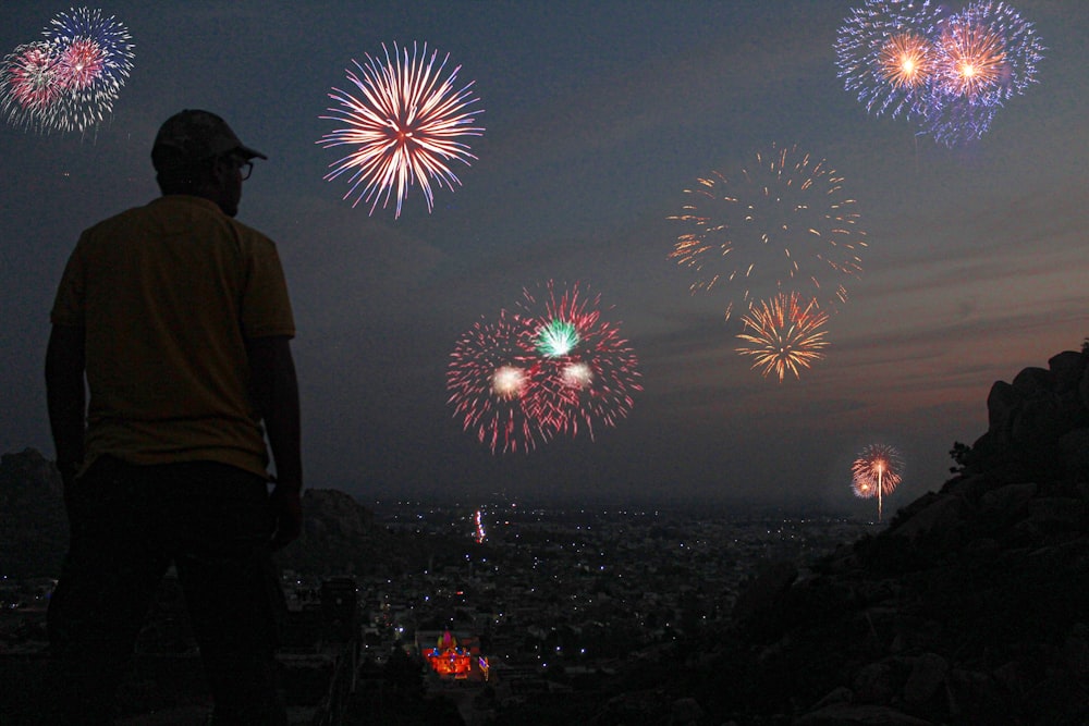 a man standing on top of a hill watching fireworks