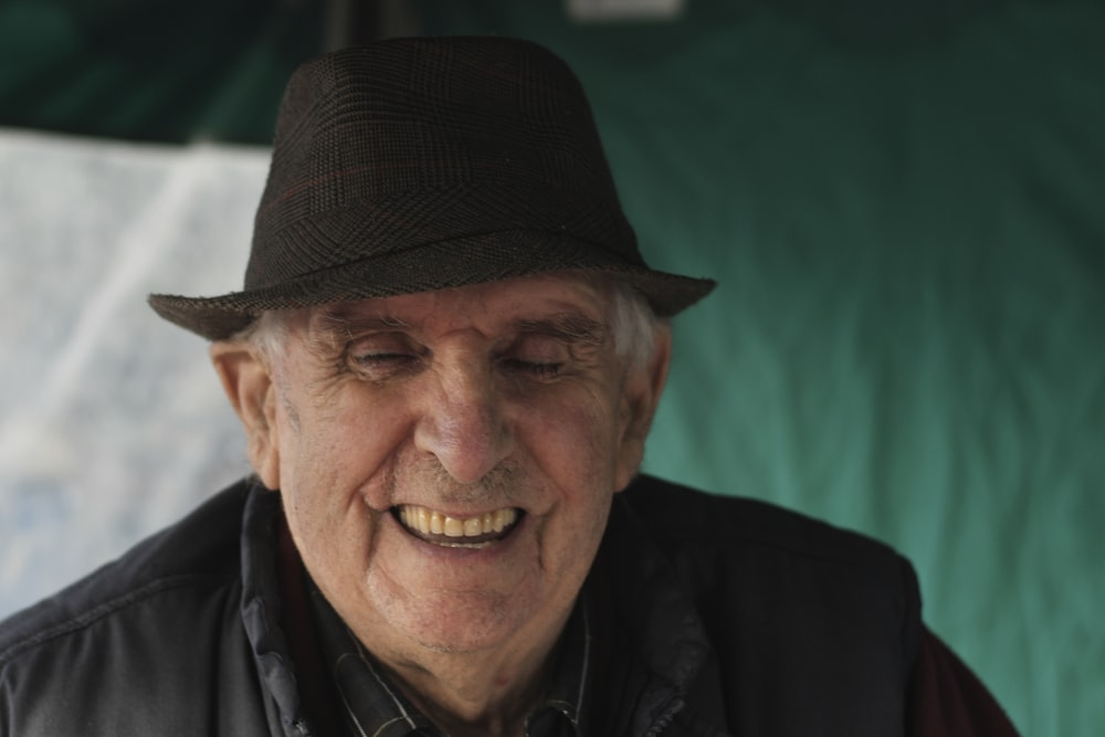 an older man wearing a hat and smiling