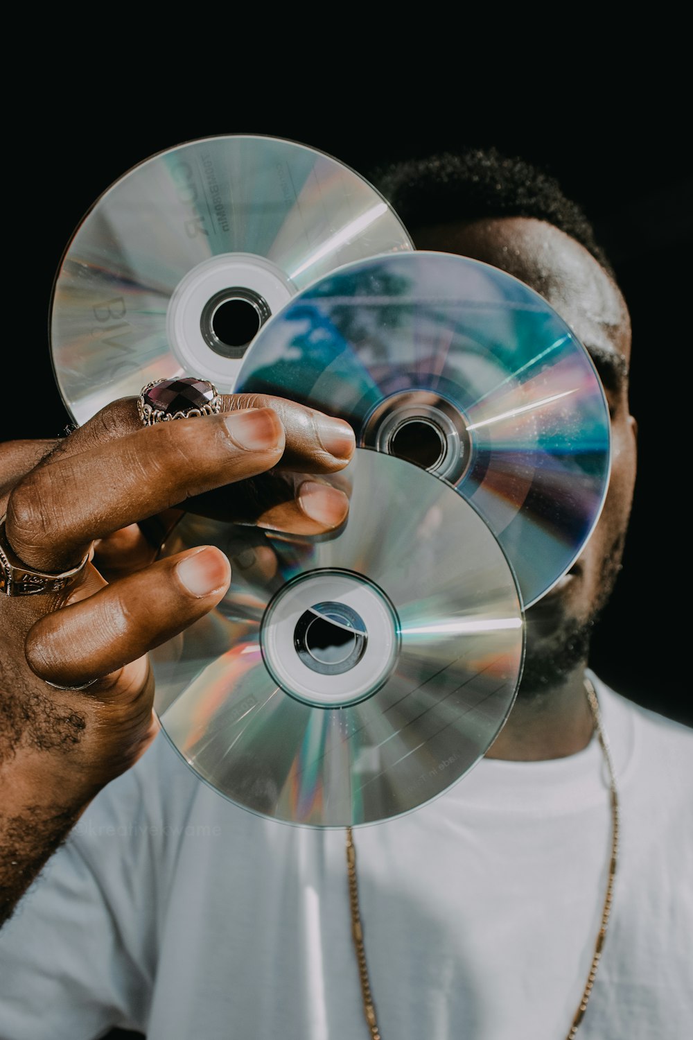 um homem segurando três cds na frente de seu rosto