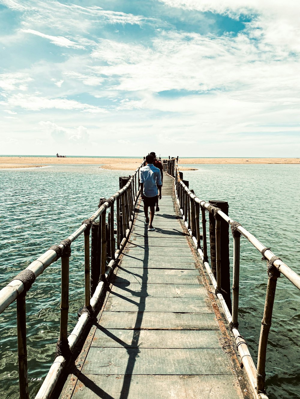 a man walking across a wooden bridge over a body of water