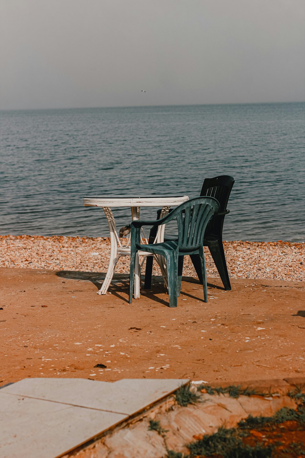 a couple of chairs and a table on a beach