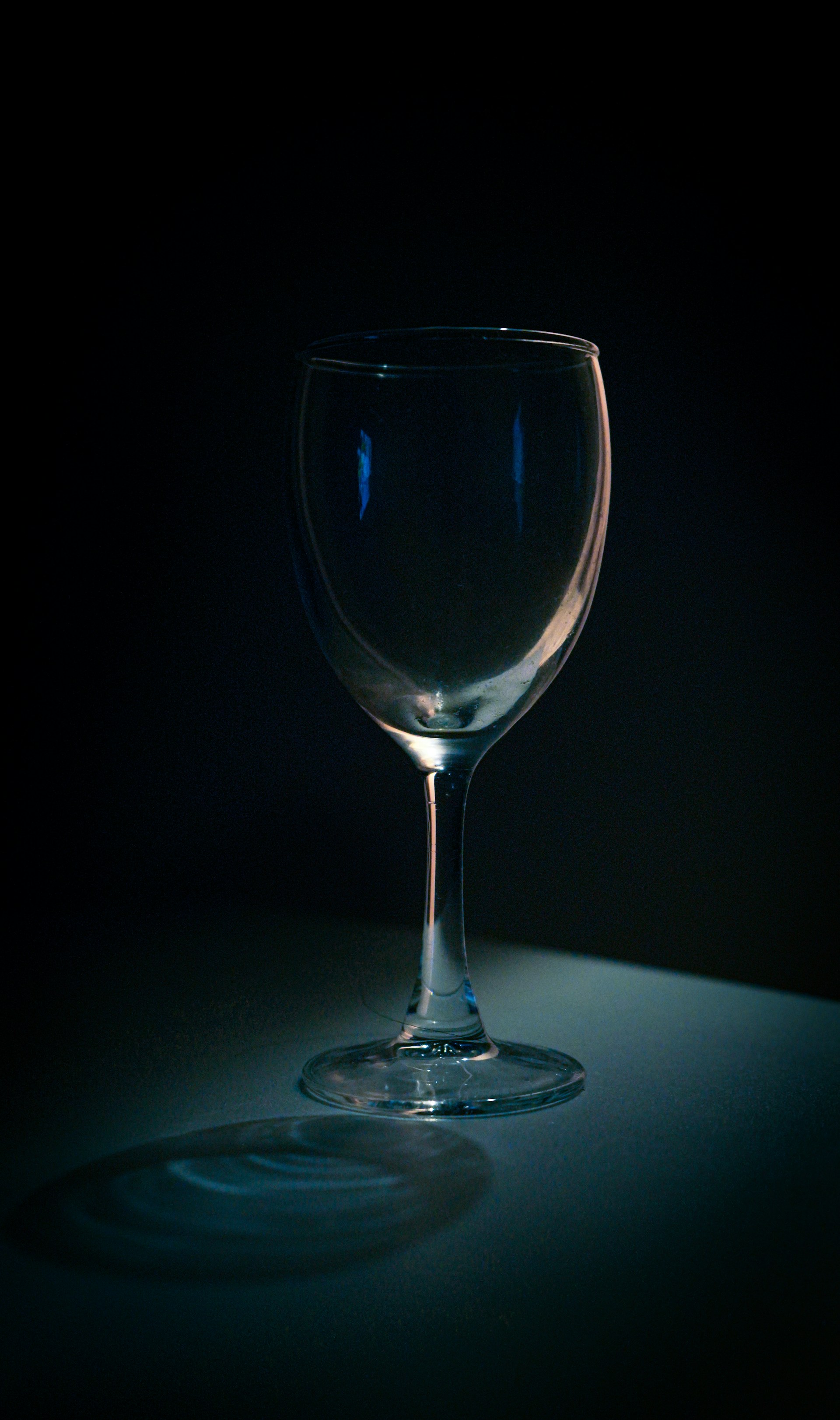 a wine glass sitting on a table in the dark