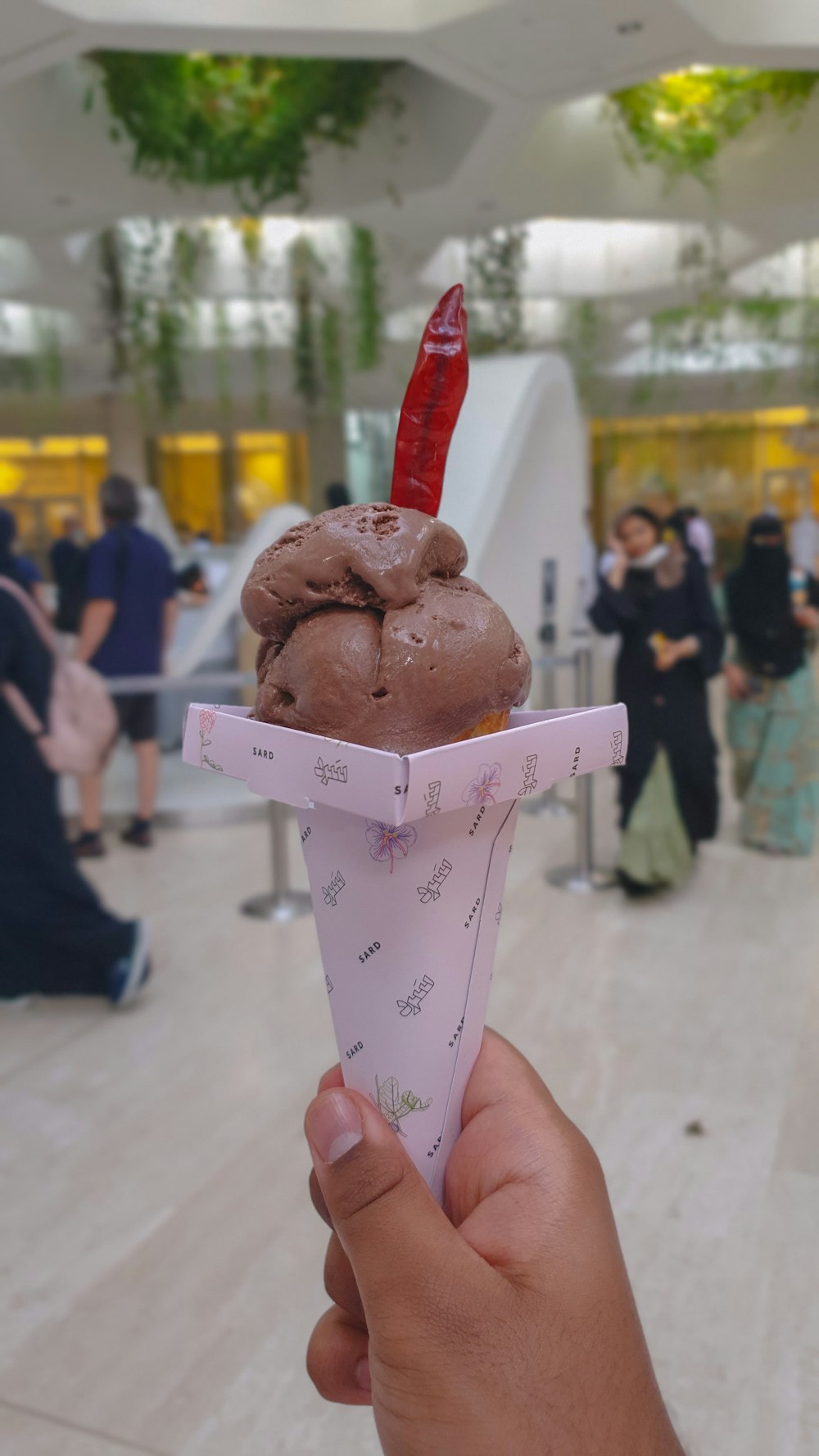 a hand holding up a chocolate ice cream cone