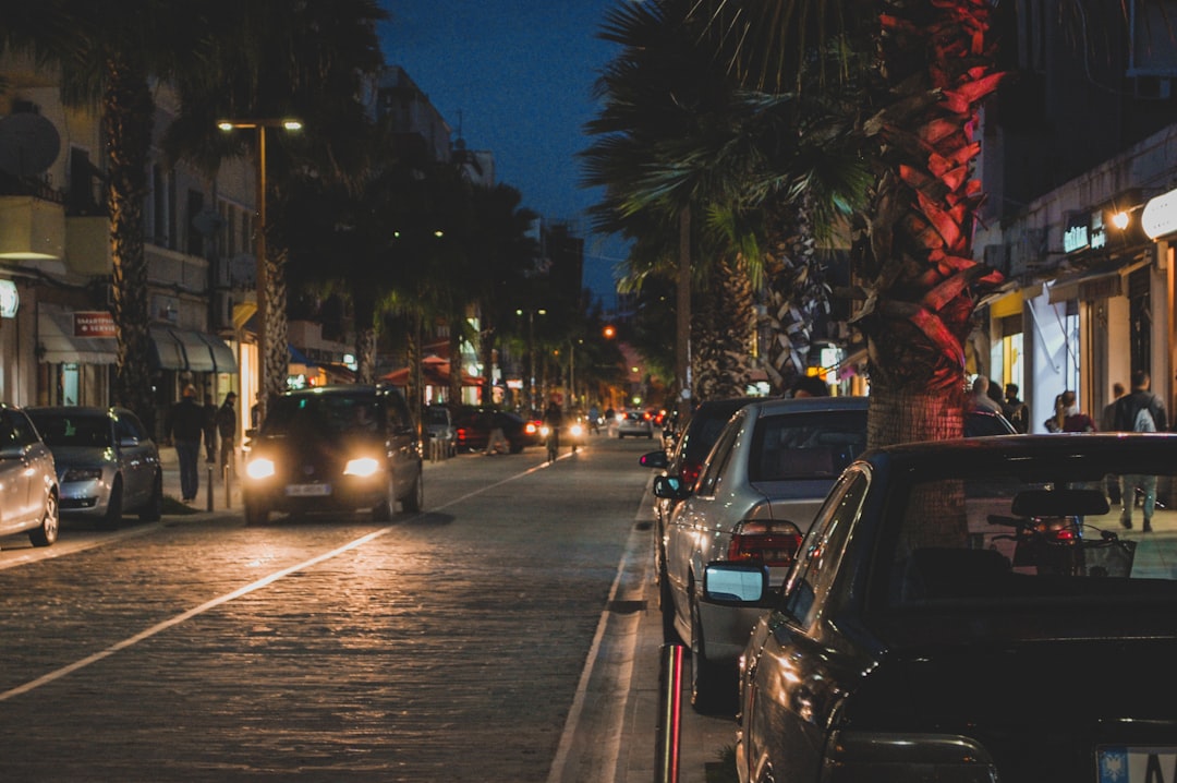 a city street at night with cars parked on the side of the street
