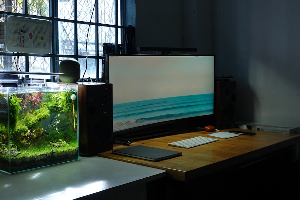 a desk with a monitor, keyboard and a fish tank