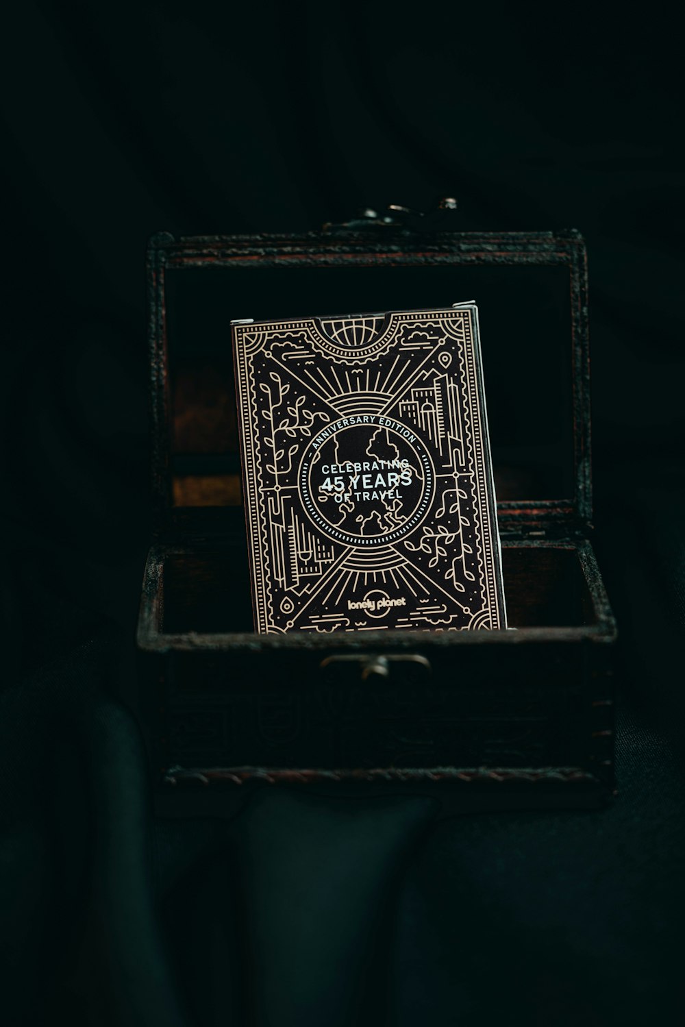 a playing card in a wooden box on a black background
