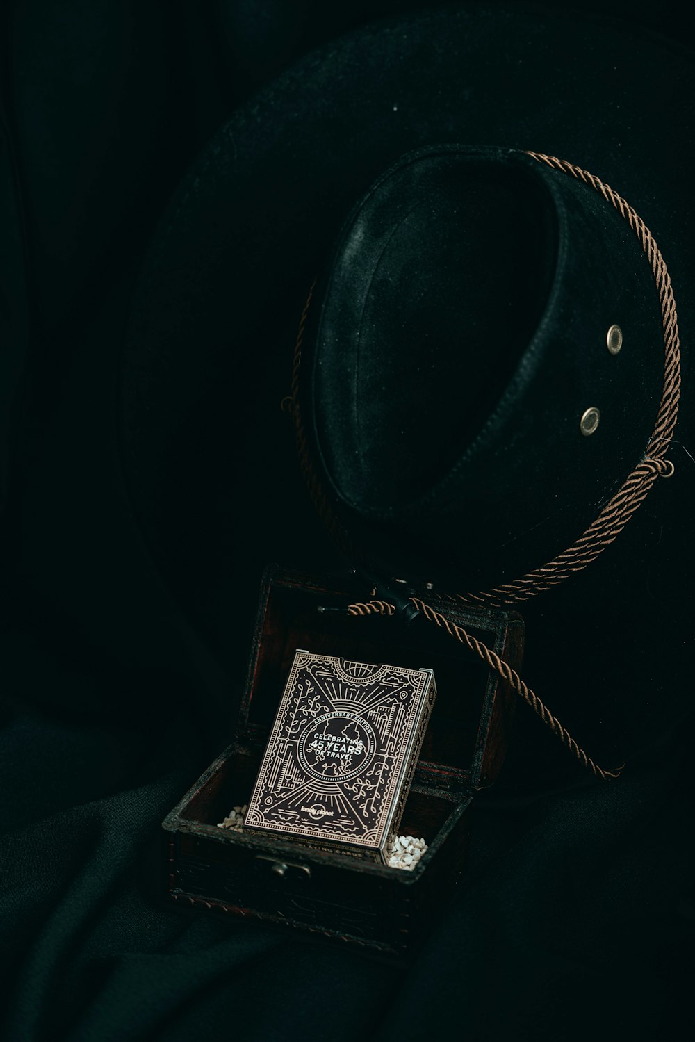 a black hat and a playing card in a wooden box