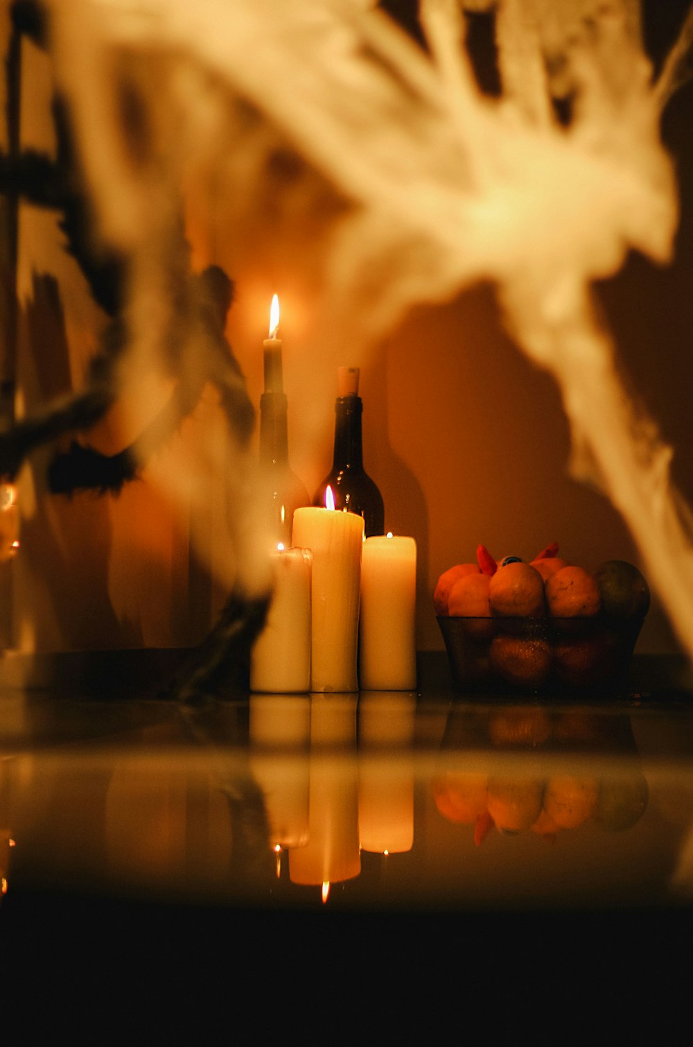 a table topped with candles next to a bowl of fruit