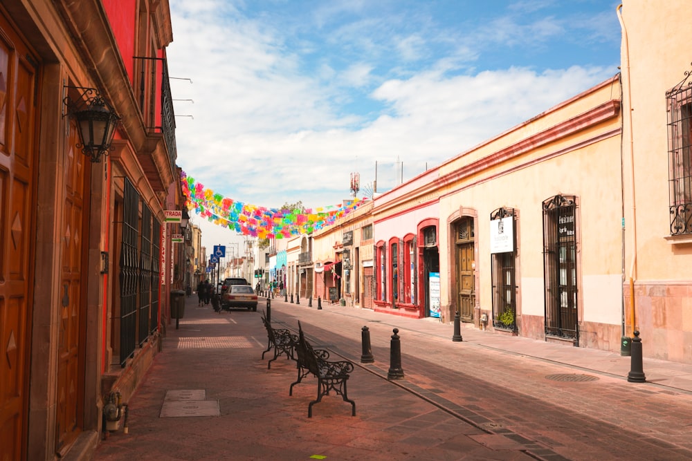 a street lined with benches and buildings under a blue sky