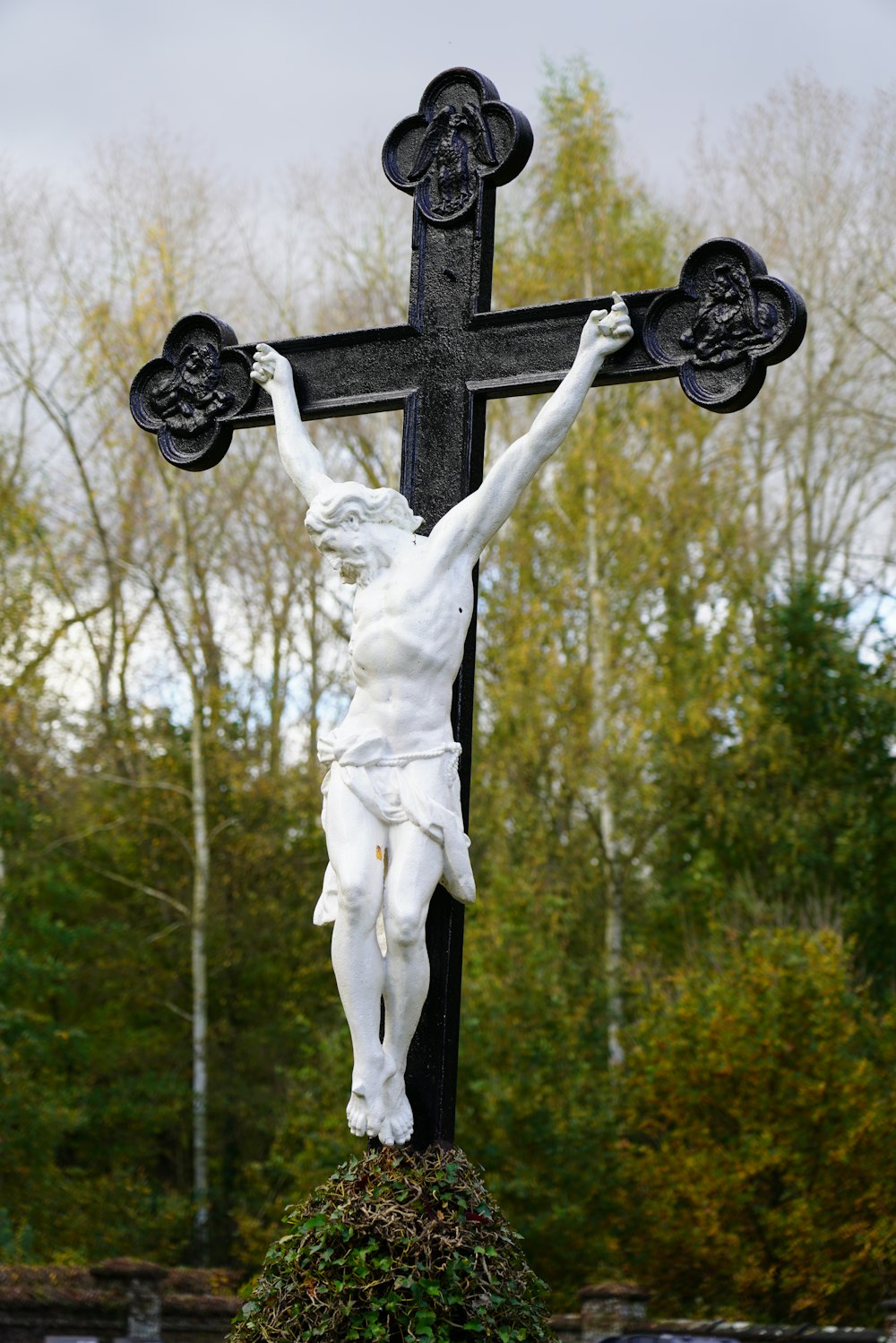 uma estátua de jesus em uma cruz em um cemitério