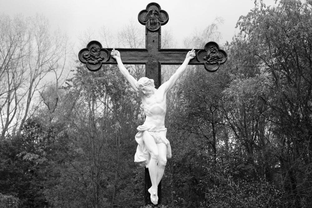 uma foto em preto e branco de uma estátua de Jesus em uma cruz