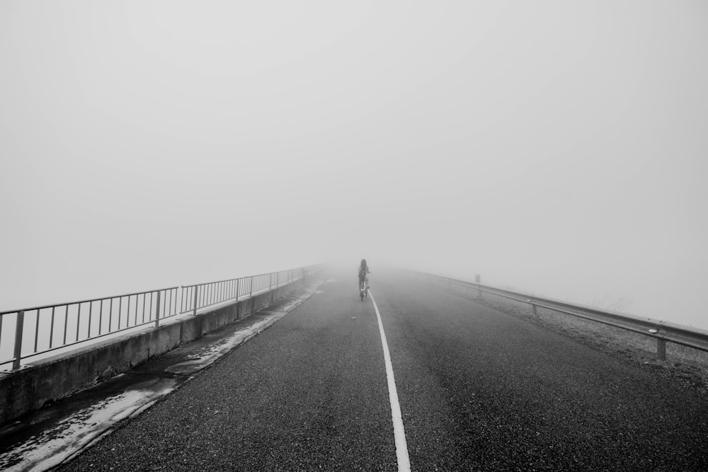 a person walking across a bridge in the fog