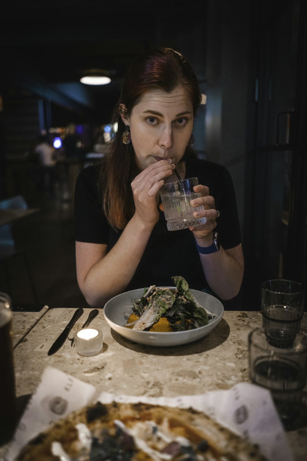 a woman sitting at a table drinking a glass of water
