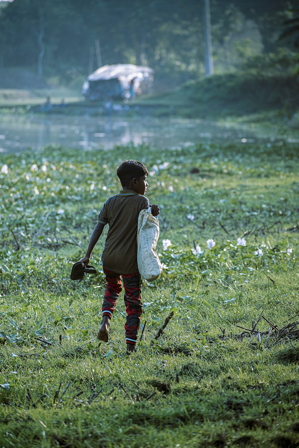 a young boy walking across a lush green field