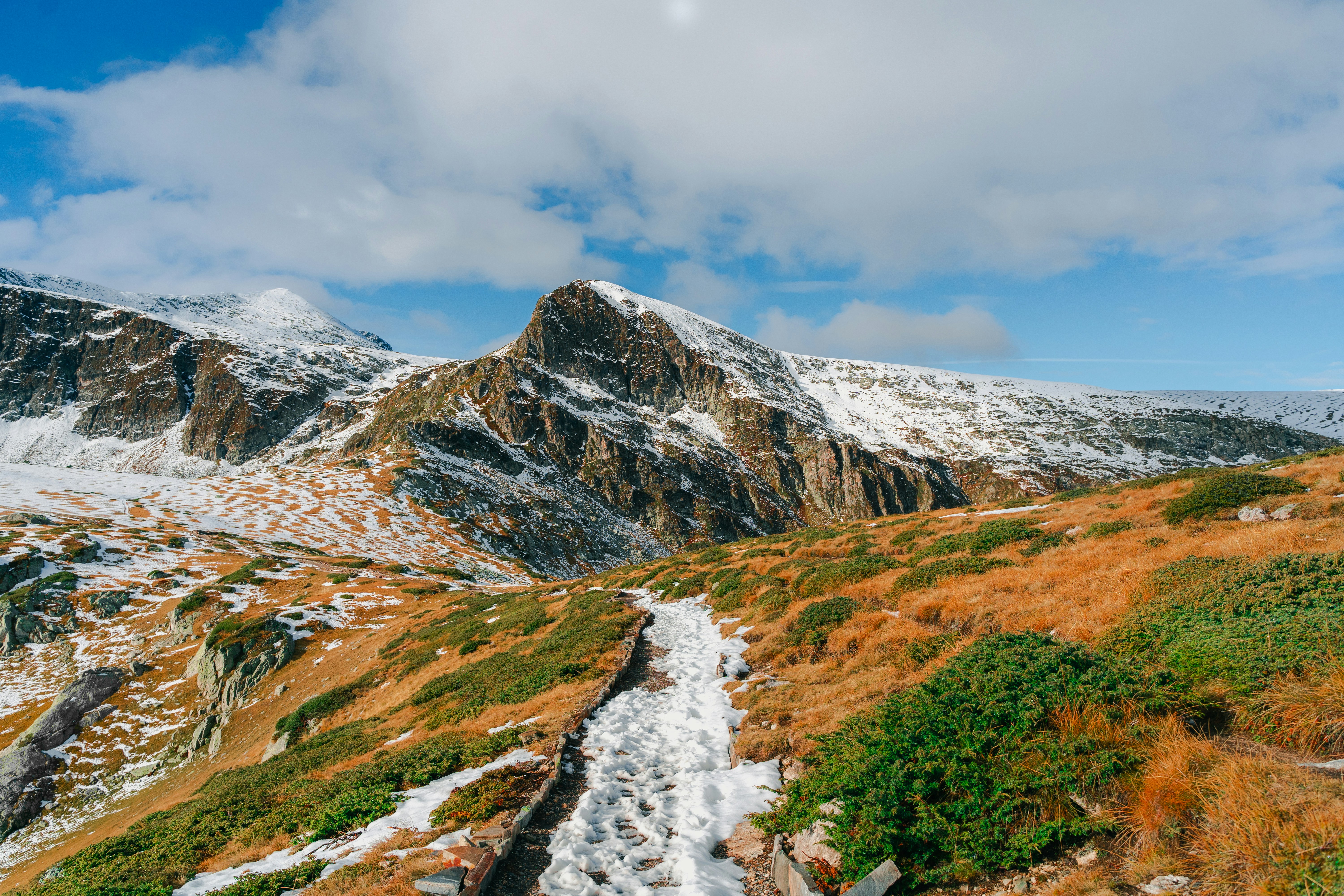 a snow covered mountain with a trail going through it, 