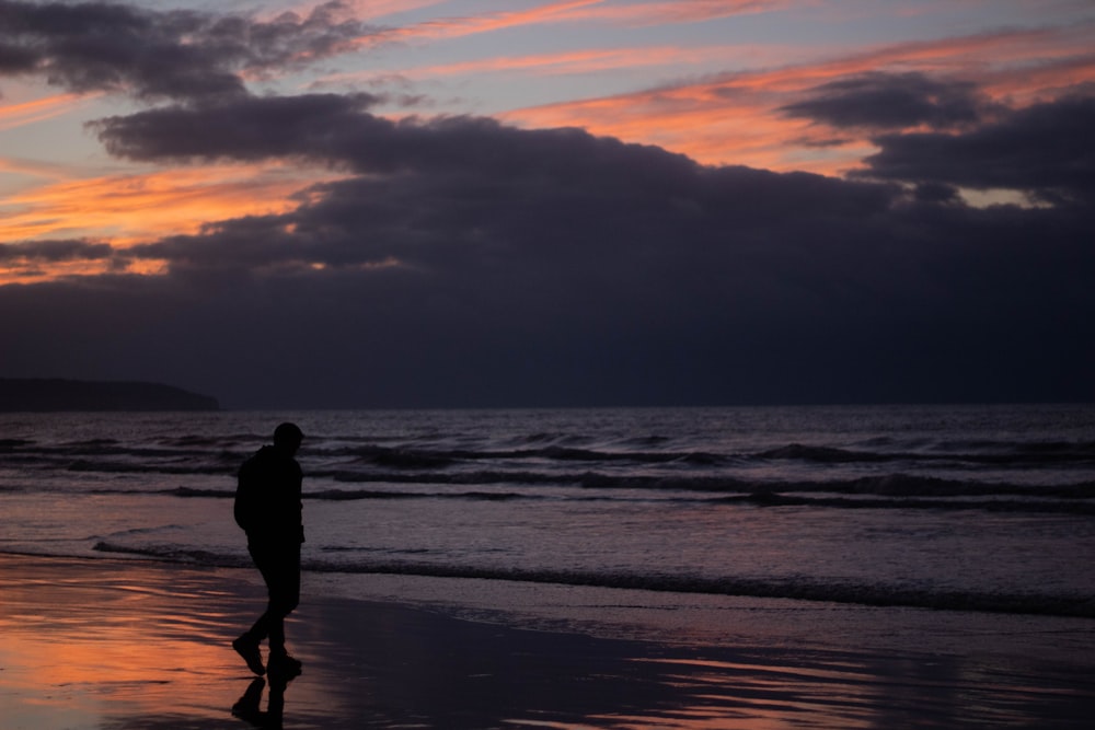 a person walking on a beach at sunset