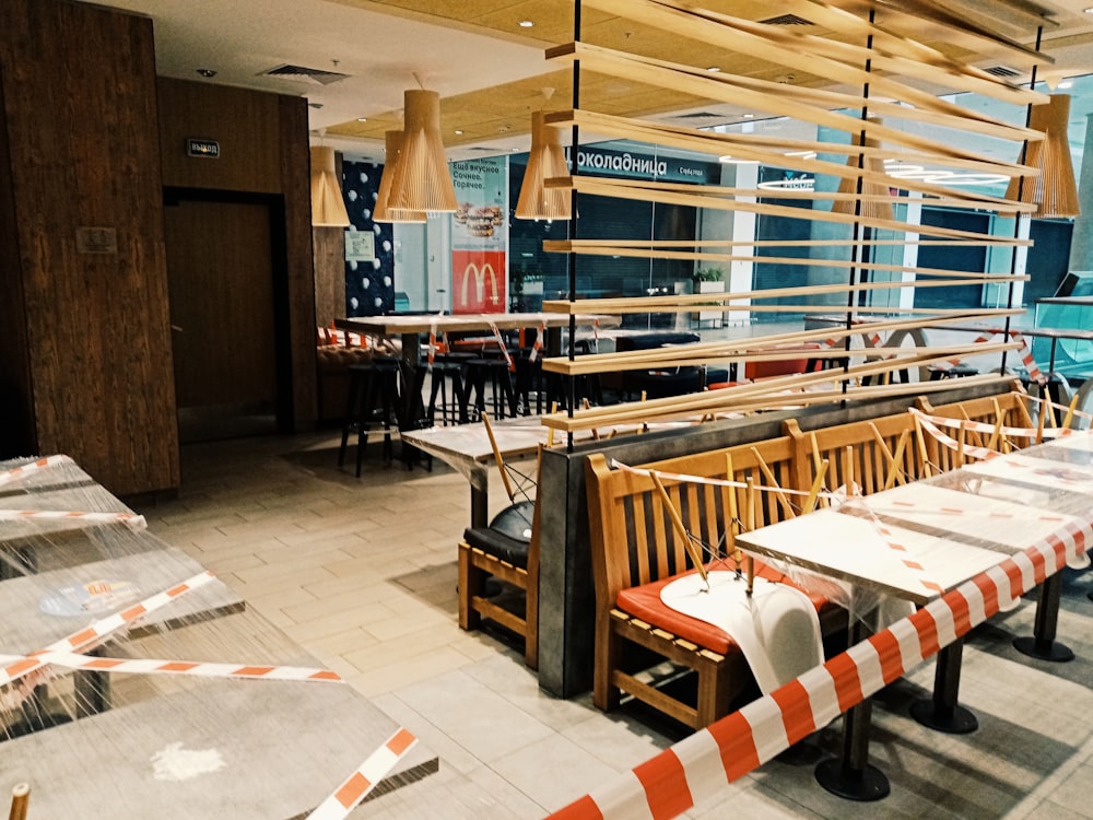 um restaurante com mesas e bancos com barreiras listradas em laranja e branco