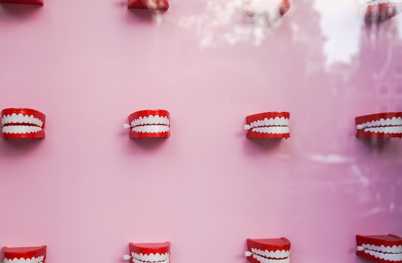 a pink wall with white teeth and braces on it