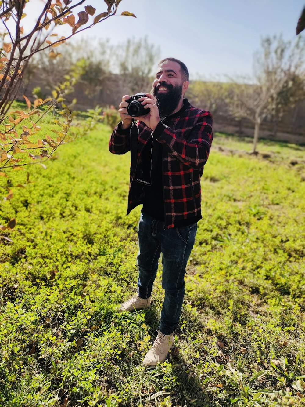 a man standing in a field taking a picture with a camera