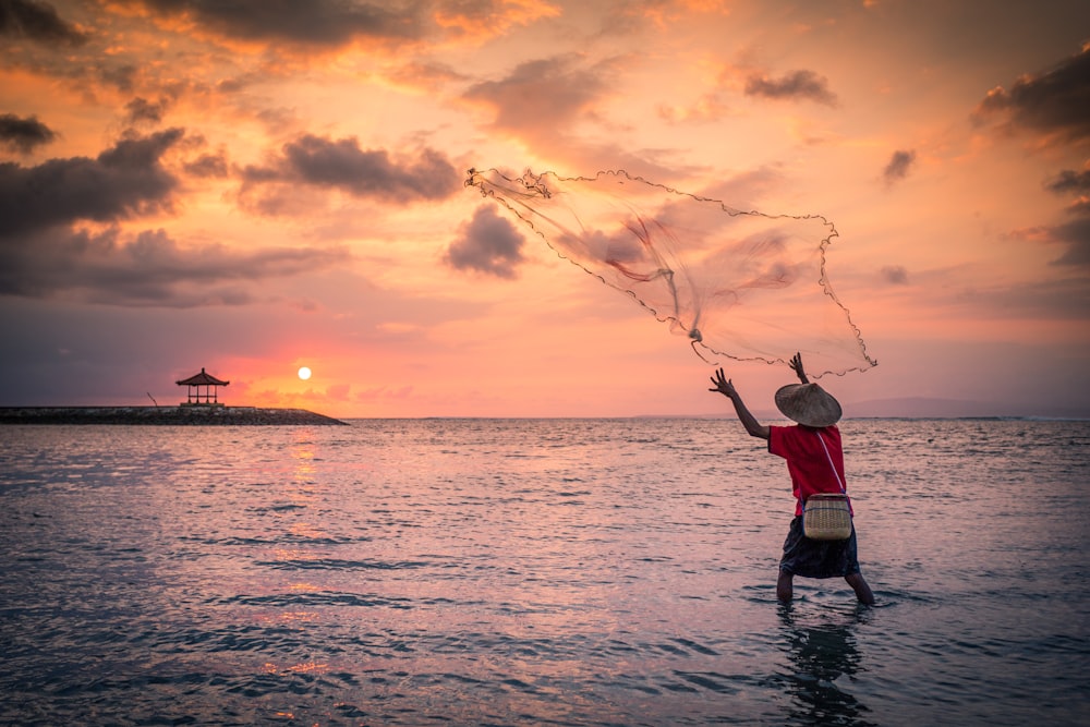 a man standing in the ocean while holding a fishing net